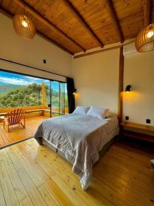 a bedroom with a bed and a large window at Cabana Mendoza - Busch Camping in Rancho Queimado