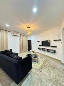 een woonkamer met een zwarte bank en een tv bij Luxury 1bedroom apartment in Accra