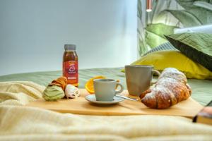 una mesa con tazas de café y cruasanes en una cama en Near the Duomo, Mini Suite Navigli, en Milán