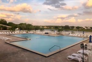 einen Pool in einem Resort mit weißen Stühlen in der Unterkunft Golfer's Paradise Ventura Resort Luxury Condo in Orlando