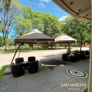 two umbrellas and chairs sitting on a patio at San Martin Plaza Hotel in Villa Elisa