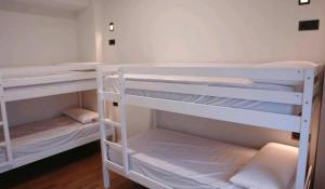 2 białe łóżka piętrowe w pokoju w obiekcie Hostel Trovadores w mieście Burgos