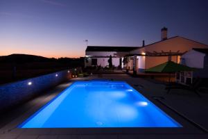 a blue swimming pool at night with a house at Monte Farropo in Monsaraz