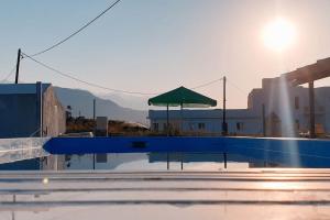 a pool with a green umbrella next to a building at Villa Kaliopi Kavros in Dhrámia