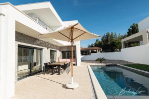 a patio with a table and an umbrella next to a swimming pool at Casa Kiara Silvercoast in Nadadouro