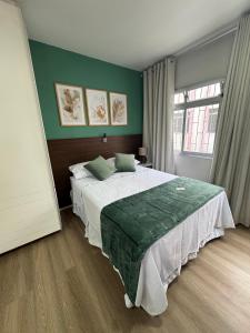 a bedroom with a large bed and a green wall at Loft Studio no Kobrasol in São José