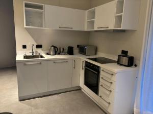 a kitchen with white cabinets and a sink at Wunderschöne Wohnung nahe Köln und Düsseldorf in Dormagen
