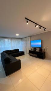 a living room with a couch and a flat screen tv at Pátio Musical Fortaleza in Foz do Iguaçu