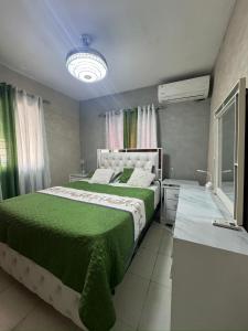 a bedroom with a large bed with a green blanket at Hermoso apartamento in Santo Domingo