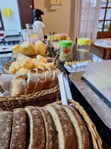 a table with bread and baskets of bread at Suítes Jardim dos Sonhos in Ubatuba