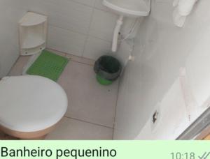 a bathroom with a white toilet and a green rug at Cantinho da casa verde em Praia Seca in Araruama