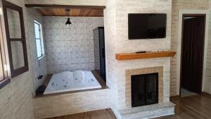 蒙特韦尔迪Chalé das Orquídeas的带壁炉和壁挂电视的浴室