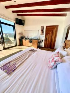 a large white bed in a room with a kitchen at Siempre Valle Hotel Boutique in Valle de Guadalupe