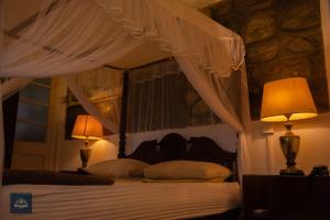 a bedroom with a canopy bed with two lamps at DEYO MIST in Kandy