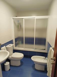 a bathroom with two toilets and a shower and a sink at O PISIÑO de AGUIÑO in Couso