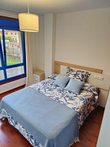 a bedroom with a bed with blue sheets and a window at O PISIÑO de AGUIÑO in Couso