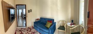 a living room with a blue chair and a table at Apartamento Centro SerraNegra in Serra Negra