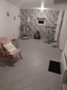 a room with a tile floor with a chair and a fireplace at Le murmure du ruisseau - Pièce de vie 60 m2 - Terrasse 30 M2 - 2 WC in Sémeries