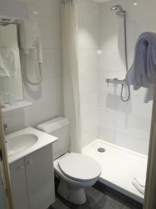 a white bathroom with a toilet and a sink at Hotel Antin St Georges in Paris