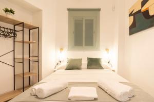 een slaapkamer met een bed met witte lakens en kussens bij Málaga Center Home in Málaga
