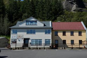 a white building with a red roof next to a parking lot at Klausturhof Guesthouse in Kirkjubæjarklaustur