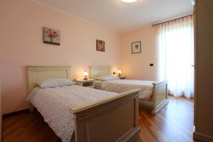 a bedroom with two beds and a window with two lamps at Agriturismo Tonutti in Tavagnacco