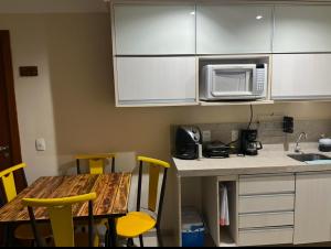 a kitchen with a table and a microwave at Quartier Aldeia das águas B-102 in Barra do Piraí
