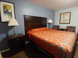 1 dormitorio con 1 cama con edredón de naranja en Brooks City Executive Inn, en San Antonio