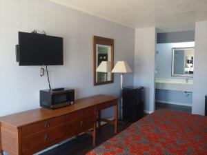 Habitación de hotel con TV y escritorio con cómoda. en Brooks City Executive Inn, en San Antonio