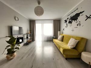a living room with a yellow couch and a tv at Apartament Zavodzie in Katowice