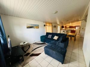 a living room with a blue couch and a kitchen at Sermie T4 à kourou avec piscine in Kourou