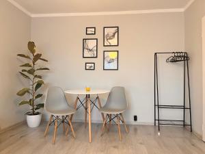a table and three chairs in a room at Apartament Zavodzie in Katowice