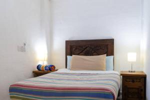 Un dormitorio con una cama con cabecero de madera y dos lámparas. en Casa ArtWalk, en Puerto Vallarta