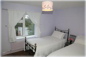 a bedroom with two beds and a window at Village House, Finuge, County Kerry in Fionnúig