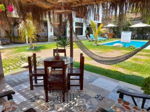 a patio with a table and chairs and a hammock at Montemar Apart Hotel - Playa Huanchaco in Huanchaco