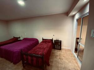 two beds in a room with purple sheets at Alojamiento Goldman in Tinogasta