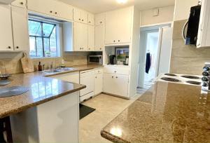 a kitchen with white cabinets and granite counter tops at Homestead Haven in Concord +11 photos