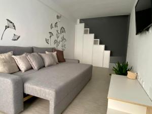 a living room with a gray couch and stairs at Soria Home-A due passi da Centro e Mare in Pesaro