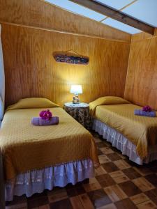 um quarto com duas camas e uma mesa com um abajur em Hostal Makohe Rapa Nui em Hanga Roa