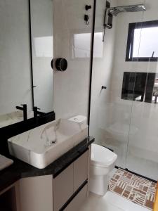 une salle de bain blanche avec un lavabo et des toilettes dans l'établissement Nosso Recanto 2 Próximo aos Pontos Turísticos, à Foz do Iguaçu 28 autres photos