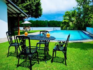 - une table et des chaises en face de la piscine dans l'établissement Okvin River Villa, à Bentota