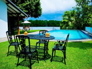 a table and chairs in front of a pool at Okvin River Villa in Bentota