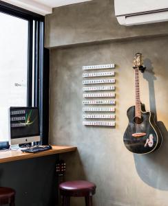 a guitar hanging on a wall next to a computer at The Mahjong in Hong Kong