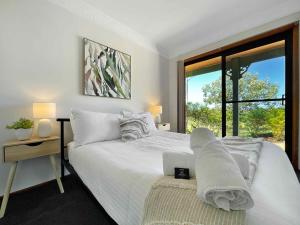 una camera da letto con un grande letto bianco con una finestra di Hunter Homestead a Lovedale