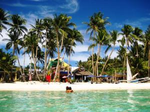 eine Person im Wasser an einem Strand mit Palmen in der Unterkunft Aquarius Terraces Boutique Resort in Boracay