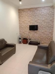 a living room with a couch and a tv on a brick wall at ARUWDA Homestay in Ipoh