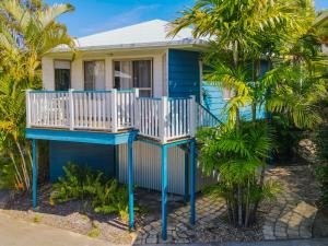 a blue house with a white deck and palm trees at Boyne Island Motel and Villas in Boyne Island
