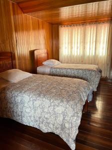 - 2 lits dans une chambre dotée de murs en bois et de parquet dans l'établissement DCampos Lodge, à Oxapampa