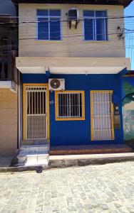 a blue building with yellow doors and windows at Flat Lua Crescente - Pituba II no coração da vila caminho das praias in Itacaré