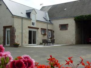 a courtyard of a house with a table and flowers at Gîte lumineux au cœur d'Épieds-en-Beauce, proche Orléans - Tout confort, animaux acceptés - FR-1-590-94 in Épieds-en-Beauce